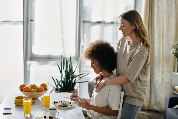A diverse lesbian couple shares a tender moment while enjoying breakfast at home. — Stock Photo