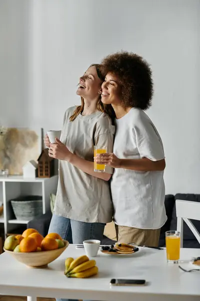 Two women, dressed casually, share a laugh together at home while enjoying breakfast. — Stock Photo