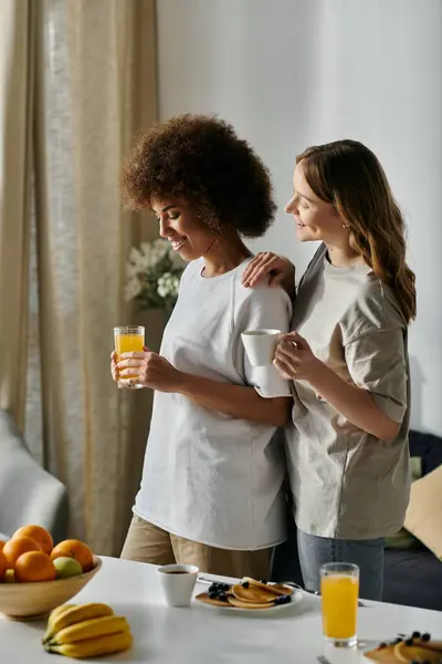 Una coppia lesbica eterogenea condivide un momento d'amore a casa durante la colazione. — Foto stock