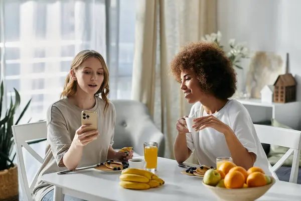 Two women enjoy a leisurely morning together at home, sharing a meal and laughter. — Stock Photo