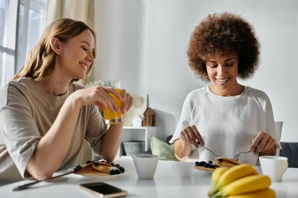 A diverse lesbian couple enjoys breakfast together at home. — Stock Photo