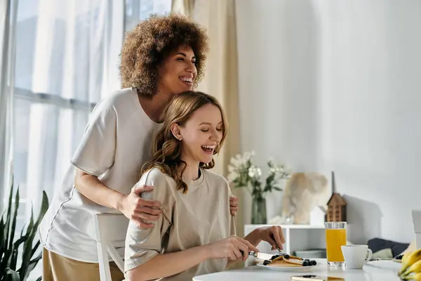 Una pareja lesbiana disfruta de una comida juntos en casa. - foto de stock