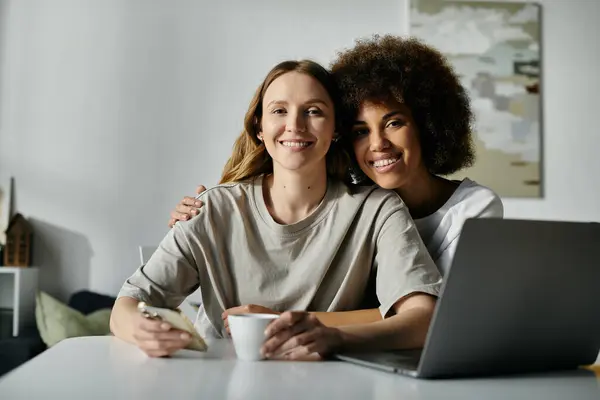 Two women, in casual attire, smile warmly at the camera while enjoying a cozy afternoon at home. — Stock Photo