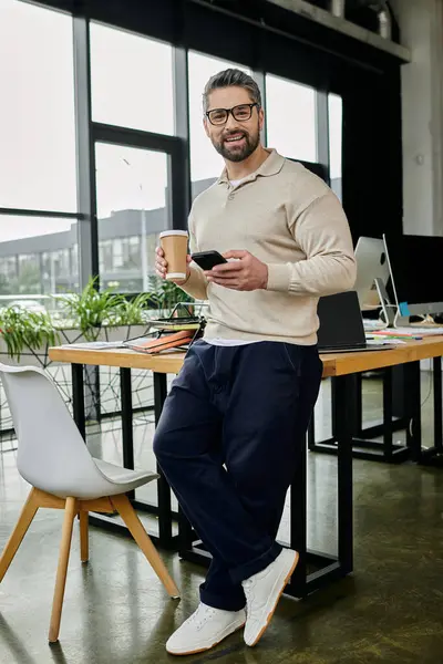 A handsome businessman with a beard smiles while looking at the camera while working in a modern office. — Stock Photo