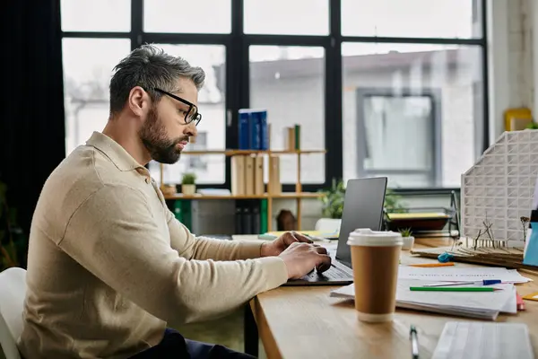 Un bell'uomo d'affari con la barba sta lavorando al suo portatile in un ufficio moderno. — Foto stock