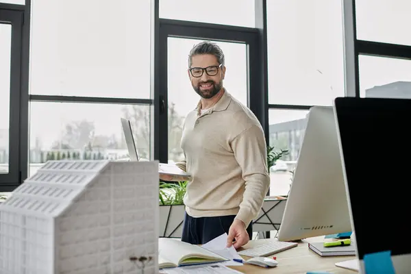 Un bel architecte avec une barbe travaille sur des plans de conception dans un bureau moderne. — Photo de stock