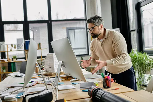 A businessman with a beard works at his computer in a modern office. The office is bright and airy, and the man looks focused and engaged. — Stock Photo