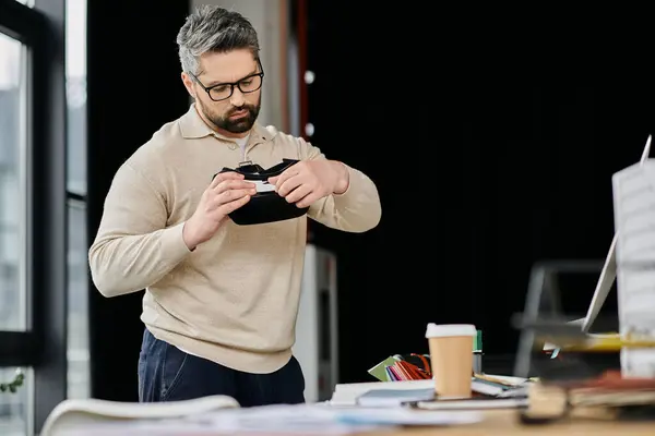 A handsome businessman with a beard adjusts his virtual reality headset while working in a modern office. — Stock Photo