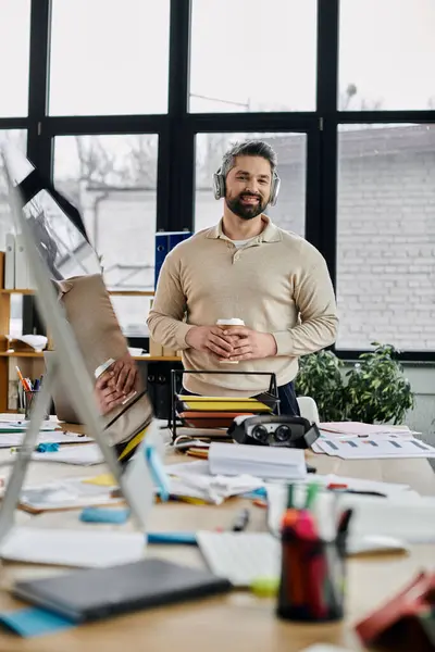A handsome bearded businessman with headphones smiles while working in a modern office. — Stock Photo