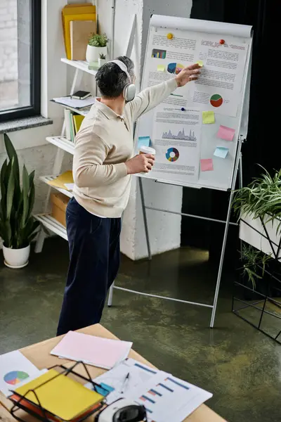 A businessman with a beard stands in a modern office, analyzing charts and graphs on a whiteboard. — Stock Photo