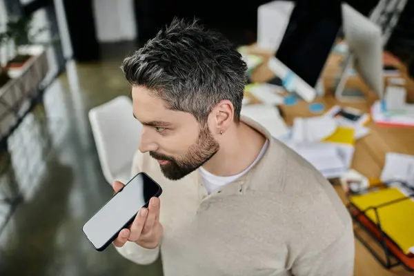 A handsome businessman with a beard is working in a modern office. He is using a voice assistant on his smartphone. — Stock Photo