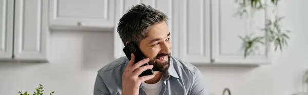 A bearded man in casual attire smiling while talking on his phone. — Stock Photo