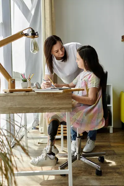 A mother helps her daughter with a prosthetic leg with her schoolwork at home. — Stock Photo