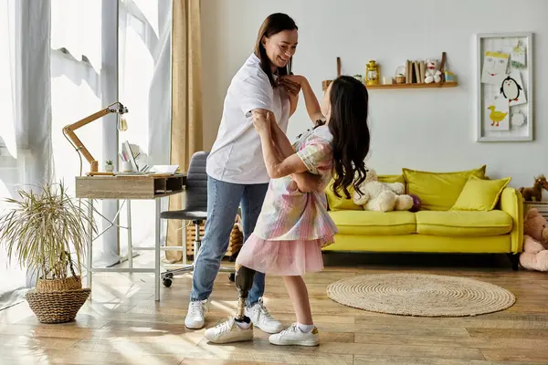 A brunette mother and her daughter with a prosthetic leg are dancing together at home. — Stock Photo