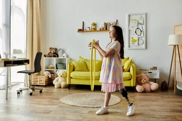 A young girl with a prosthetic leg plays with a hula hoop in her living room, demonstrating her joyful spirit and ability to embrace life. — Stock Photo