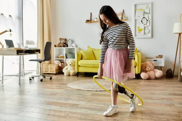 A young girl with a prosthetic leg holds a hula hoop in a home playroom, showcasing her strength and playful spirit. — Stock Photo