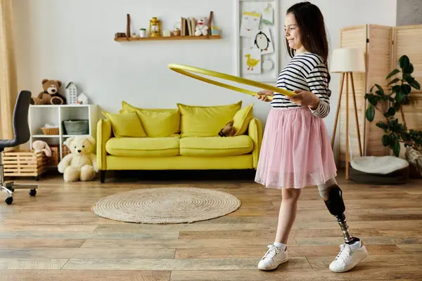Uma jovem com uma perna protética brinca alegremente com um arco de hula em sua sala de estar. — Fotografia de Stock