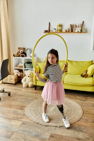 Ein junges Mädchen mit Beinprothese spielt in ihrem Haus mit einem Hula-Hoop-Reifen. — Stockfoto