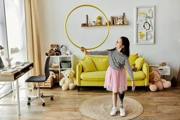 Молода дівчина з протезною ногою обертається жовтим обручем у своєму будинку, демонструючи свою радість і силу. — стокове фото