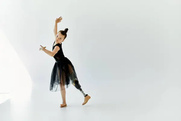 A young girl in a black leotard and tutu performs a graceful pose, showcasing her talent and determination as a gymnast with a prosthetic leg. — Stock Photo