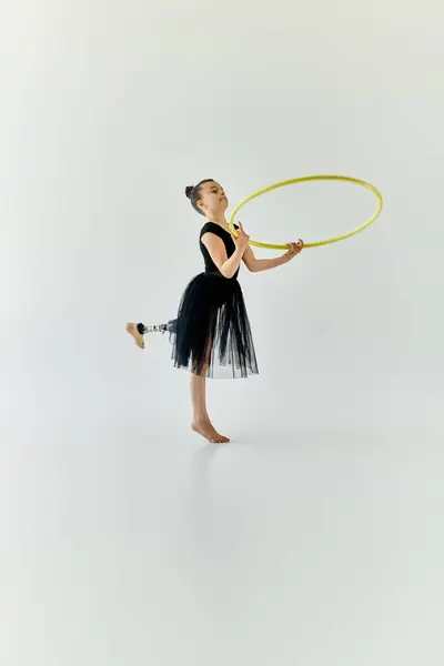 Une jeune fille avec une jambe prothétique manœuvre gracieusement un cerceau pendant une routine de gymnastique. — Photo de stock