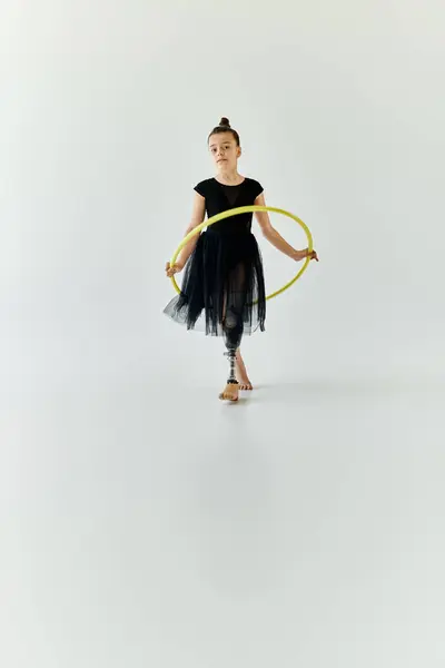 Ein junges Mädchen mit Beinprothese führt in einem weißen Studio eine Hula-Hoop-Übung durch. — Stockfoto