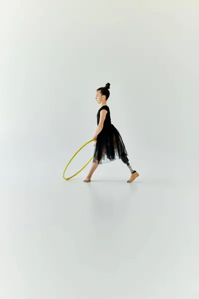 Ein junges Mädchen mit Beinprothese turnt mit einem Reifen in einem weißen Studio. — Stockfoto