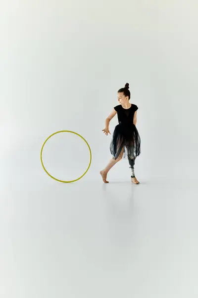 A young girl with a prosthetic leg practices gymnastics with a hula hoop. — Stock Photo