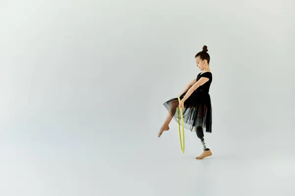 A young girl with a prosthetic leg practices gymnastics using a hula hoop. — Stock Photo