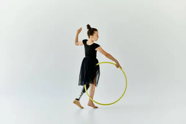 A young girl with a prosthetic leg performs gymnastics with a hoop in a studio setting. — Stock Photo