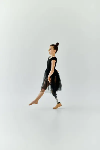 A young girl with a prosthetic leg performs a graceful step in a ballet studio. — Stock Photo
