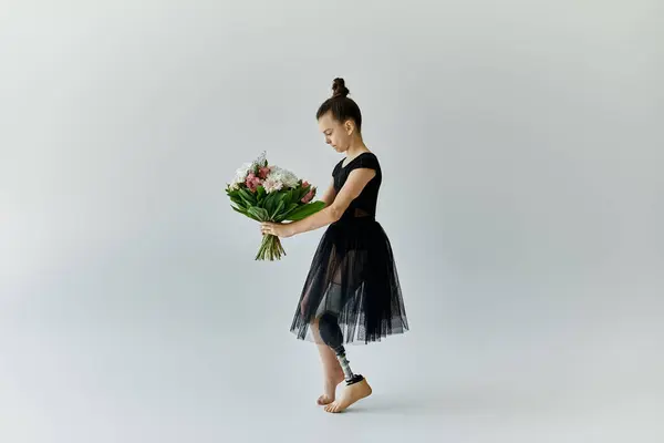 Uma jovem com uma perna protética segura um buquê de flores enquanto usa um colete de ginástica preto e tutu. — Fotografia de Stock