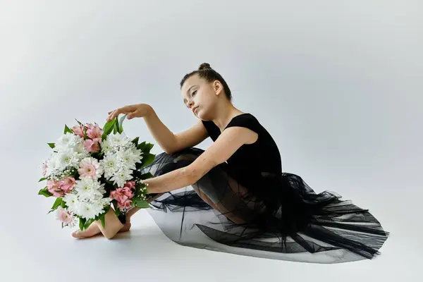 A young girl with a prosthetic leg in a black leotard and tutu holds a bouquet of flowers. — Stock Photo