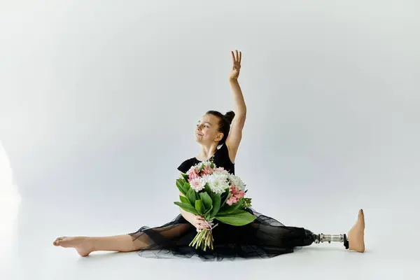 Ein junges Mädchen mit Beinprothese vollführt eine anmutige Stretchübung in einem schwarzen Trikot. — Stockfoto