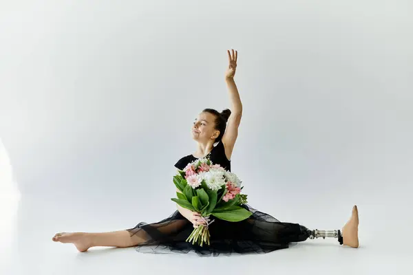 A young girl with a prosthetic leg performs a graceful stretch in a black leotard. — Stock Photo