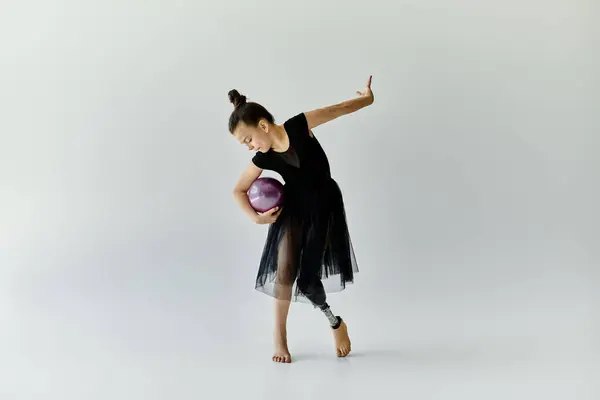 A young girl with a prosthetic leg performs a gymnastics routine with a purple ball. — Stock Photo