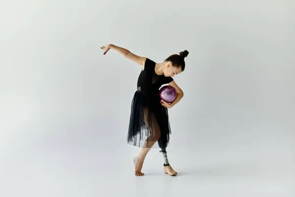 A young girl with a prosthetic leg performs a gymnastic routine with a ball. — Stock Photo