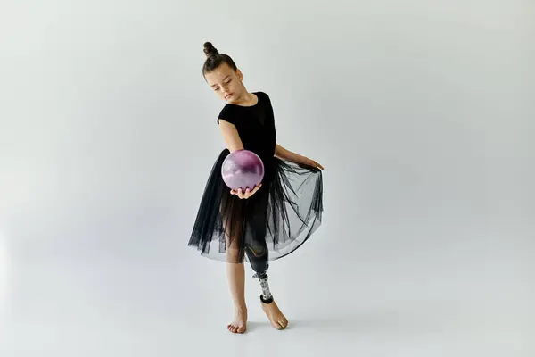 A young gymnast with a prosthetic leg performs a graceful routine with a purple ball. — Stock Photo