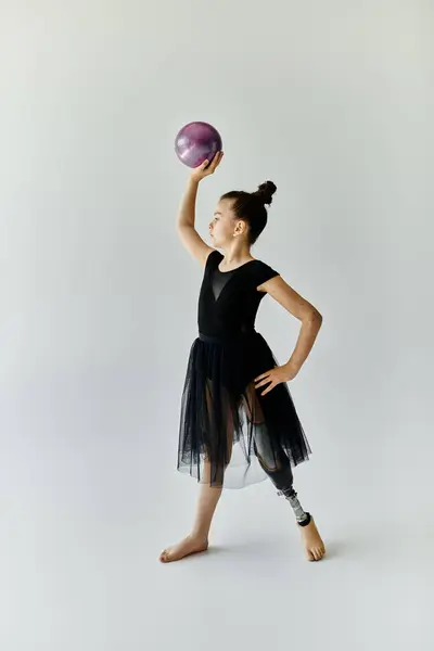 Ein junges Mädchen in schwarzem Trikot und Rock turnt mit Beinprothese. — Stockfoto