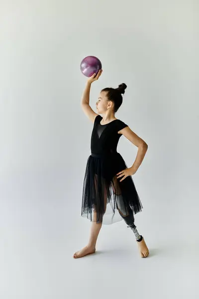 A young girl in a black leotard and skirt practices gymnastics with a prosthetic leg. — Stock Photo