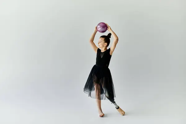 Ein junges Mädchen mit Beinprothese turnt mit Ball im Studio. — Stockfoto