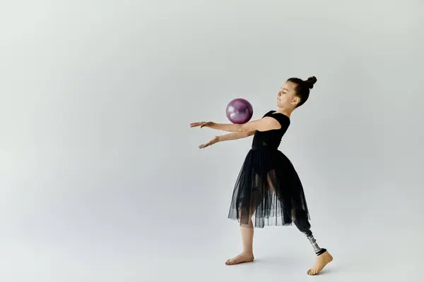 A young girl with a prosthetic leg performs a rhythmic gymnastics routine with a ball. — Stock Photo