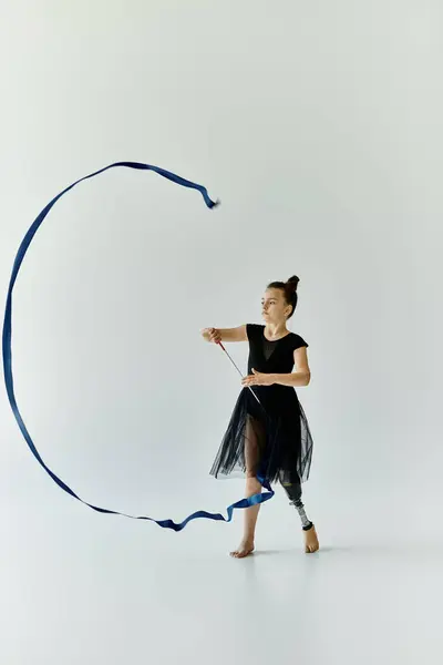 A young gymnast with a prosthetic leg gracefully manipulates a ribbon during a performance. — Stock Photo