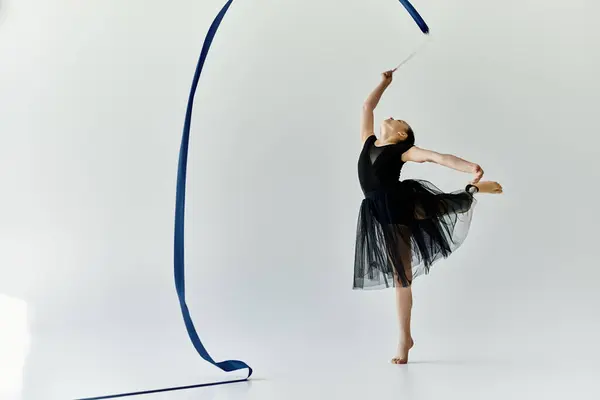 Une jeune fille avec une jambe prothétique effectue une routine de gymnastique gracieuse avec un ruban bleu. — Photo de stock