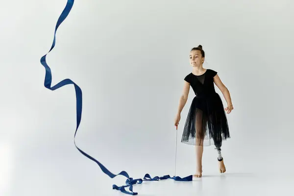 A young girl with a prosthetic leg gracefully performs a ribbon routine in a gymnastics studio. — Stock Photo