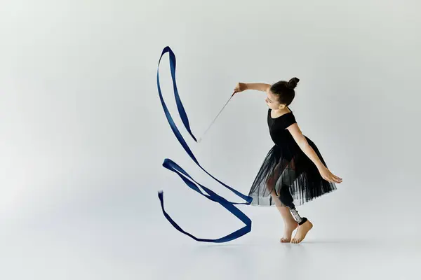 Ein junges Mädchen mit Beinprothese führt während einer Gymnastikeinheit eine anmutige Schleifenübung durch. — Stockfoto