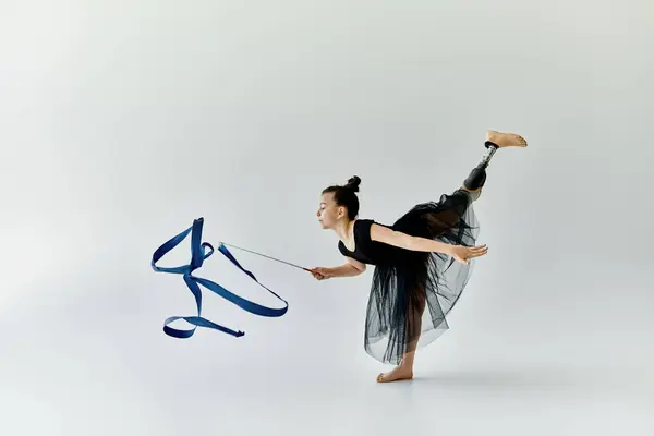 A young girl with a prosthetic leg performs a graceful gymnastics routine with a ribbon. — Stock Photo