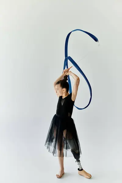 A young girl with a prosthetic leg performs a graceful gymnastics routine with a ribbon. — Stock Photo