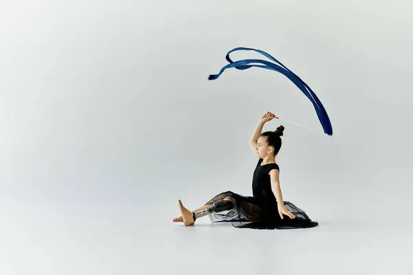 Una giovane ragazza con una gamba protesica pratica la sua routine di ginnastica con un nastro blu. — Stock Photo