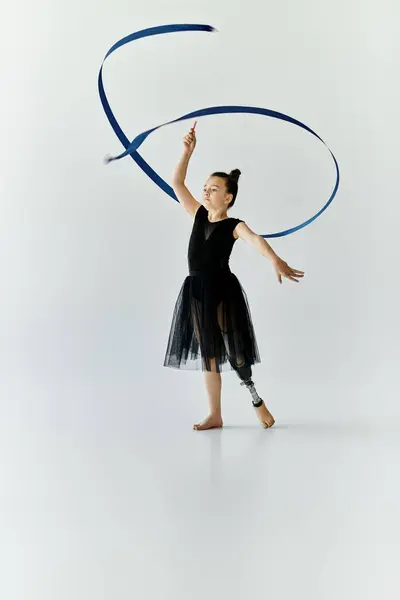 A young girl with a prosthetic leg performs a graceful ribbon routine in a studio. — Stock Photo